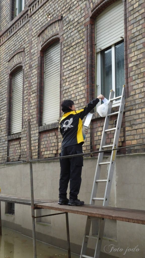 Hochwasser in St. Goarshausen: Eine Postbotin stellt Briefe durchs Fenster zu. Foto: Josef Schmitt.